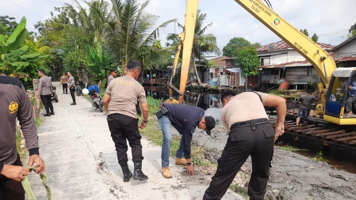 Gotong Royong Personel Polda Riau dan Warga Bersihkan Bantaran Sungai di Dumai Jelang Peresmian Jembatan oleh Kapolri
